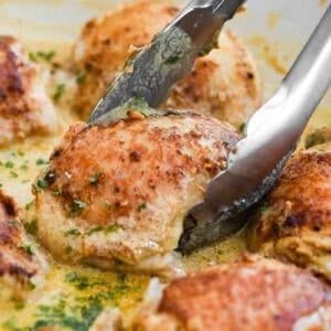 Taking a piece of French mustard chicken with tongs.