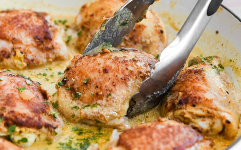 Taking a piece of French mustard chicken with tongs.