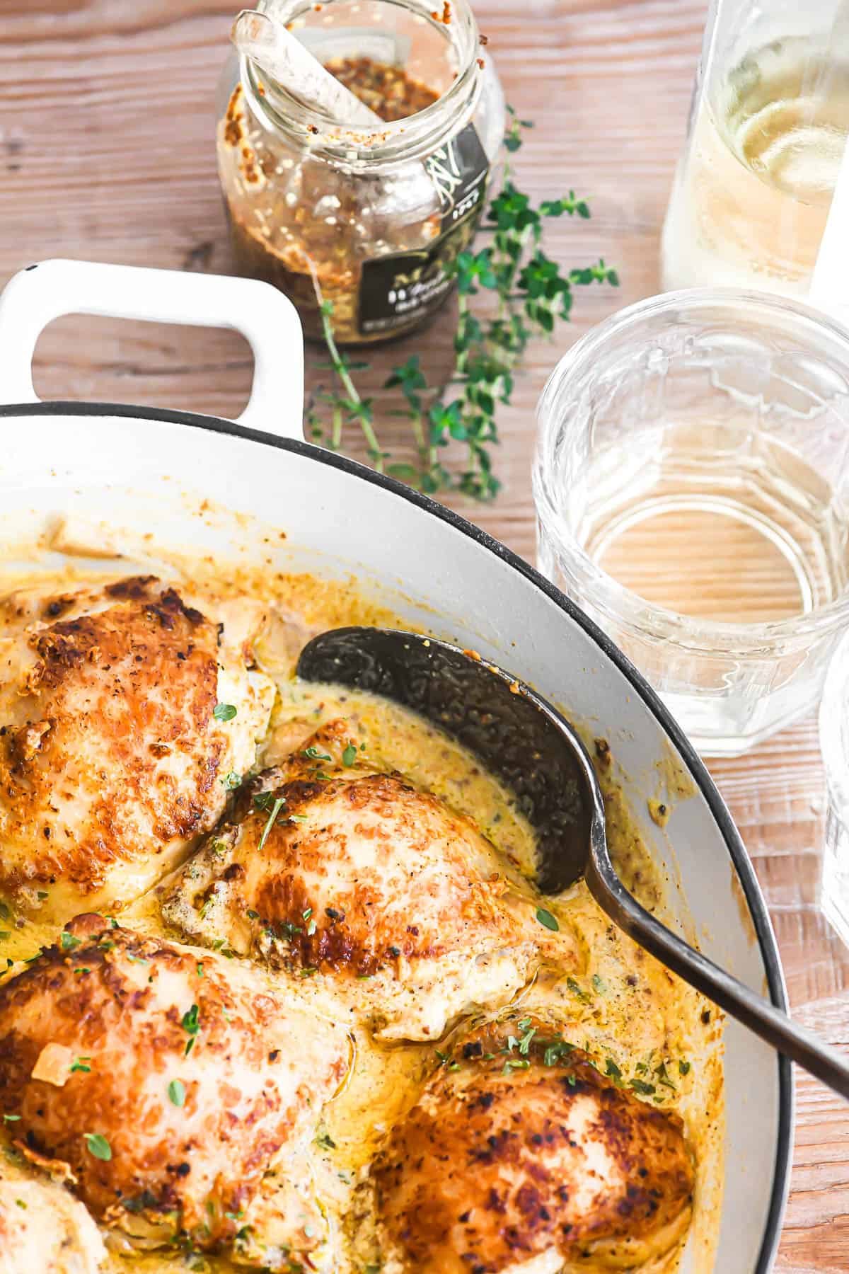 French mustard chicken in a braising pan with thyme and white wine.