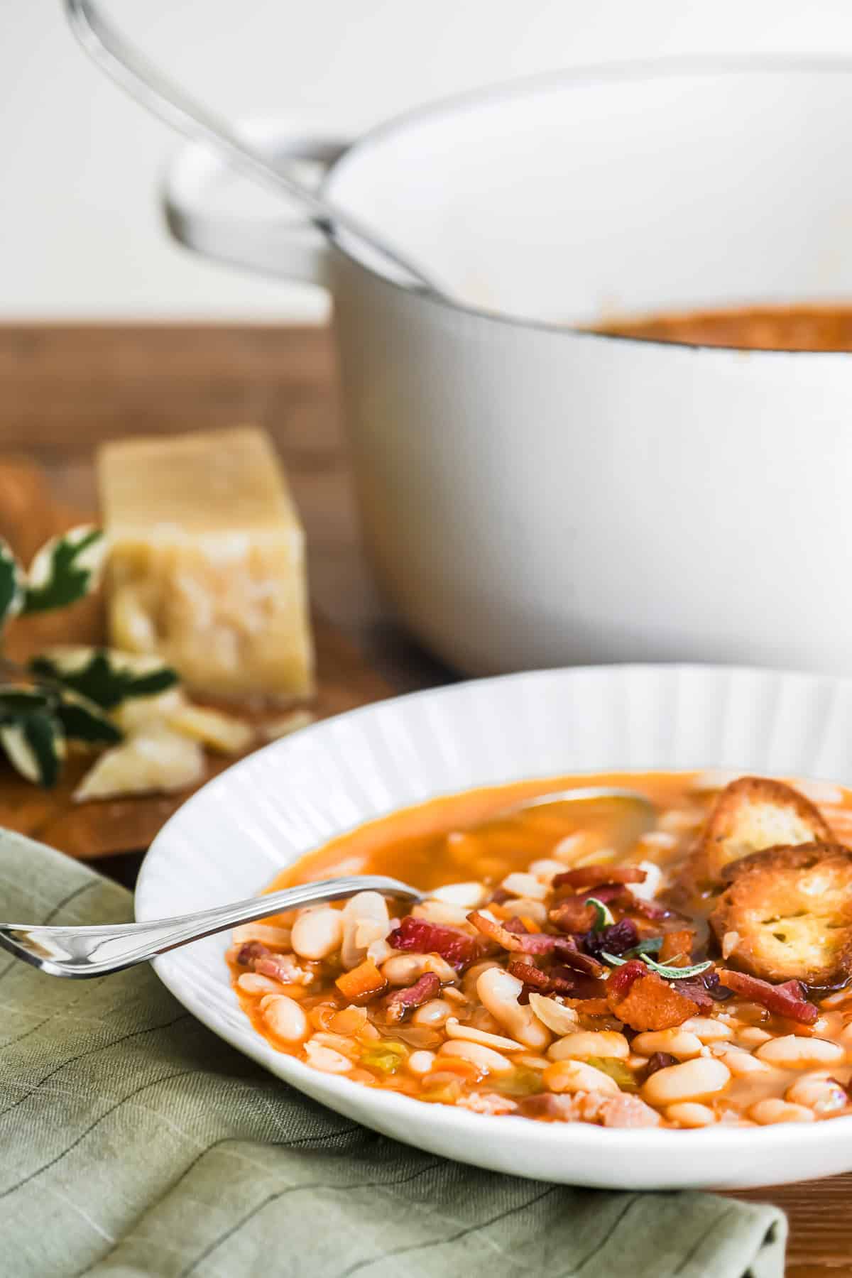 a bowl of white bean and bacon soup with Dutch oven in background.