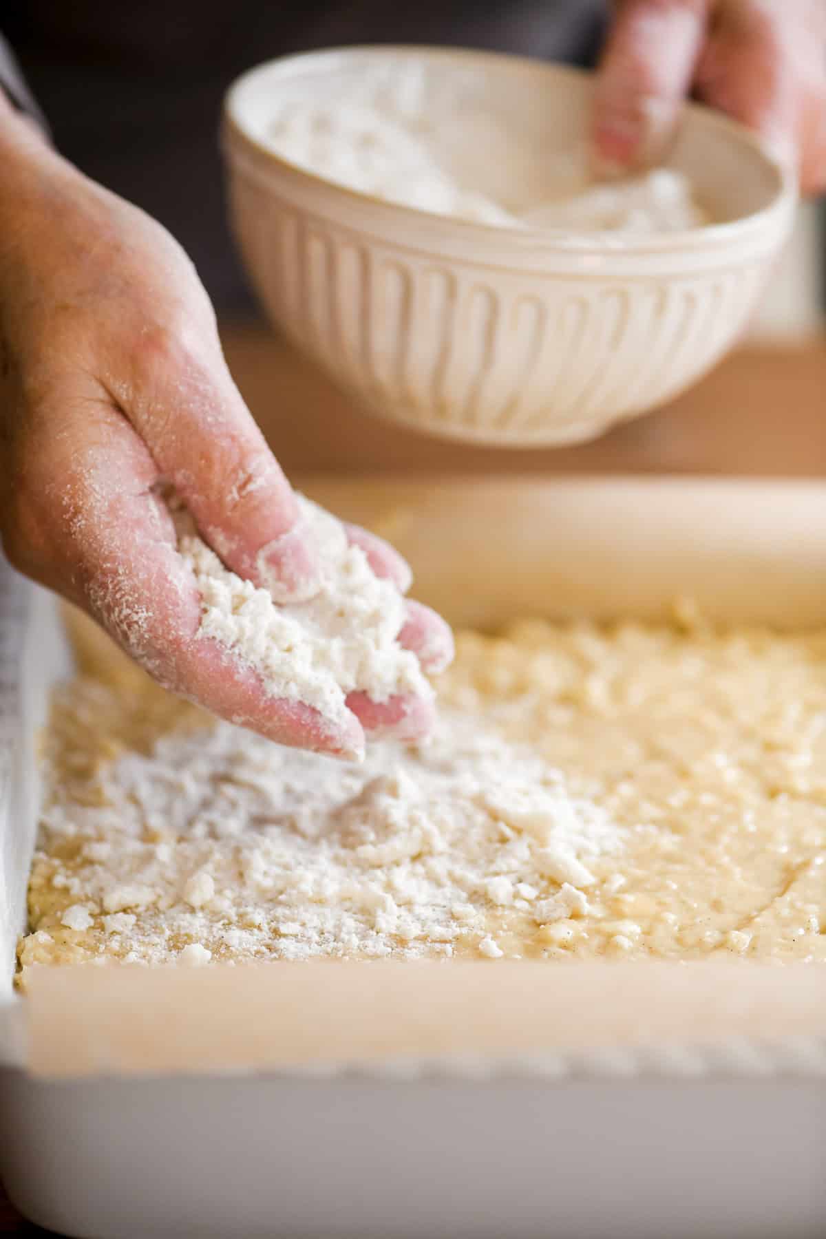 Adding crumbs to the top of cardamom crumb cake.