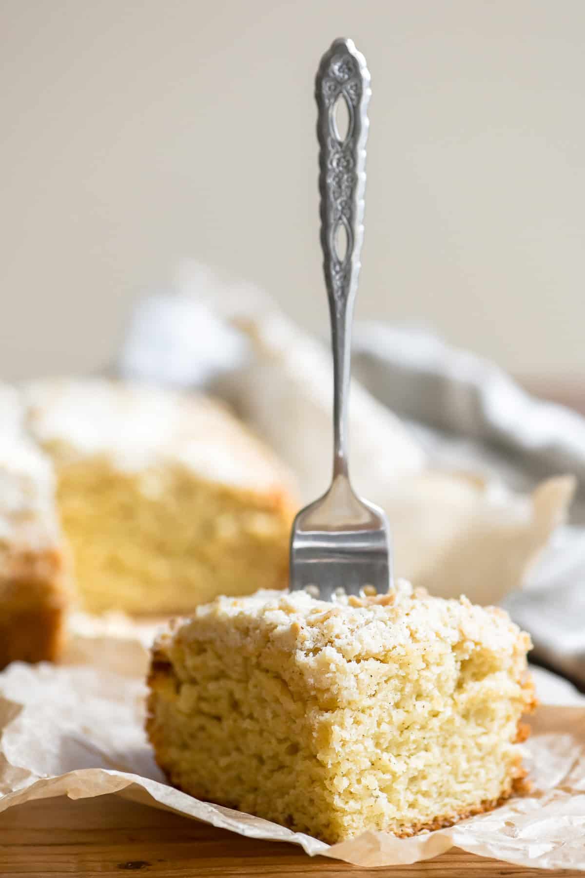 a slice of cardamom crumb cake with a fork stuck in it.