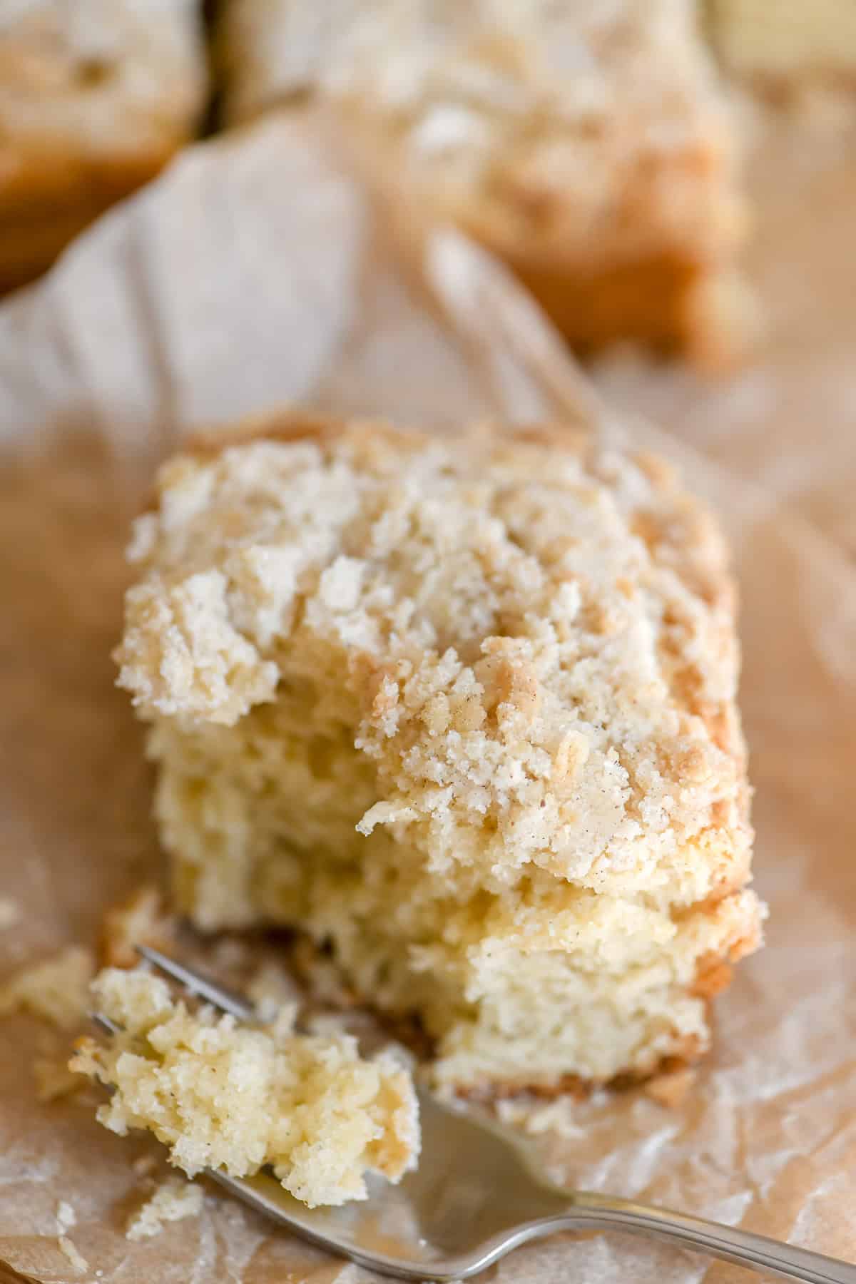 A piece of cardamom crumb cake with bite taken.