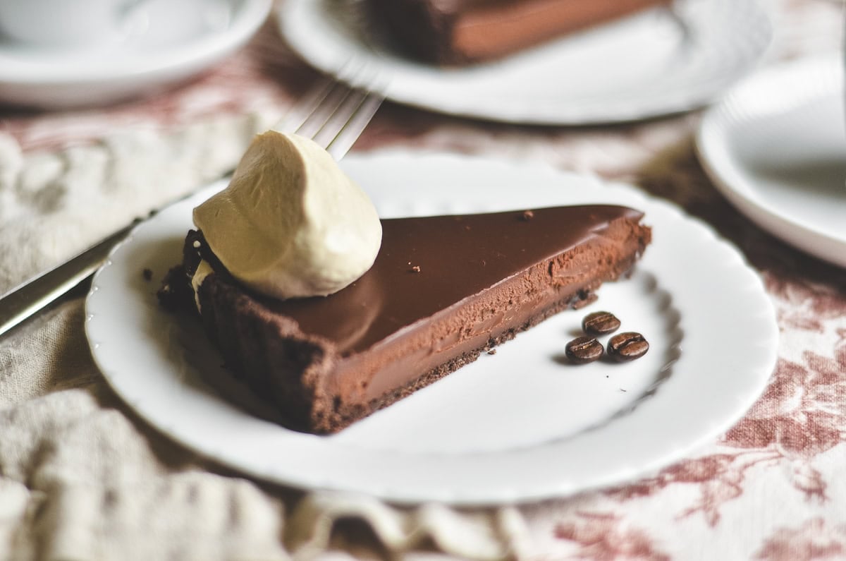 a slice of espresso ganache tart topped with a dollop of coffee whipped cream.