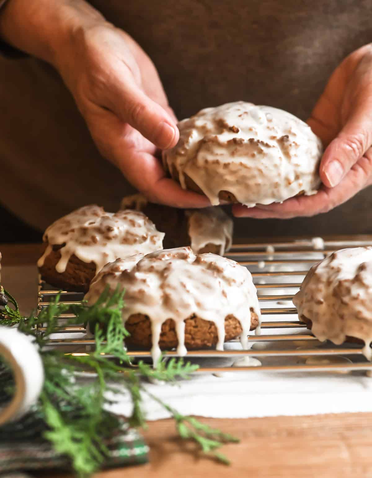 holding a glazed gingerbread scones, with more on a rack.