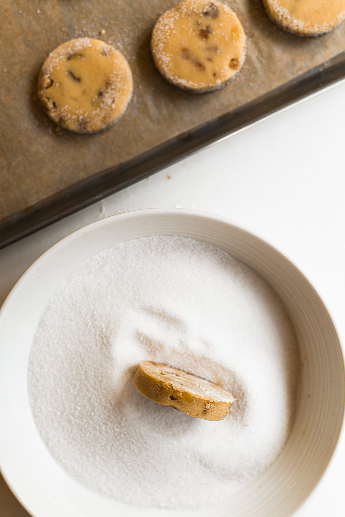 Rolling maple walnut shortbread cookie in sugar.
