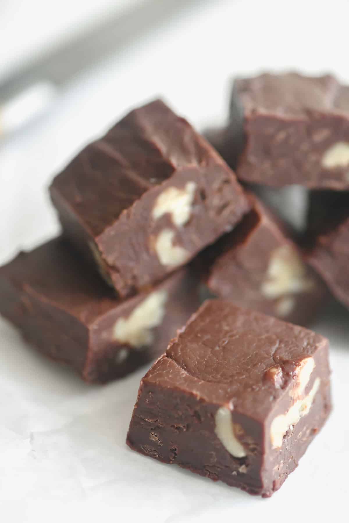 Microwave fudge with walnuts, tumbled on parchment paper, with knife.
