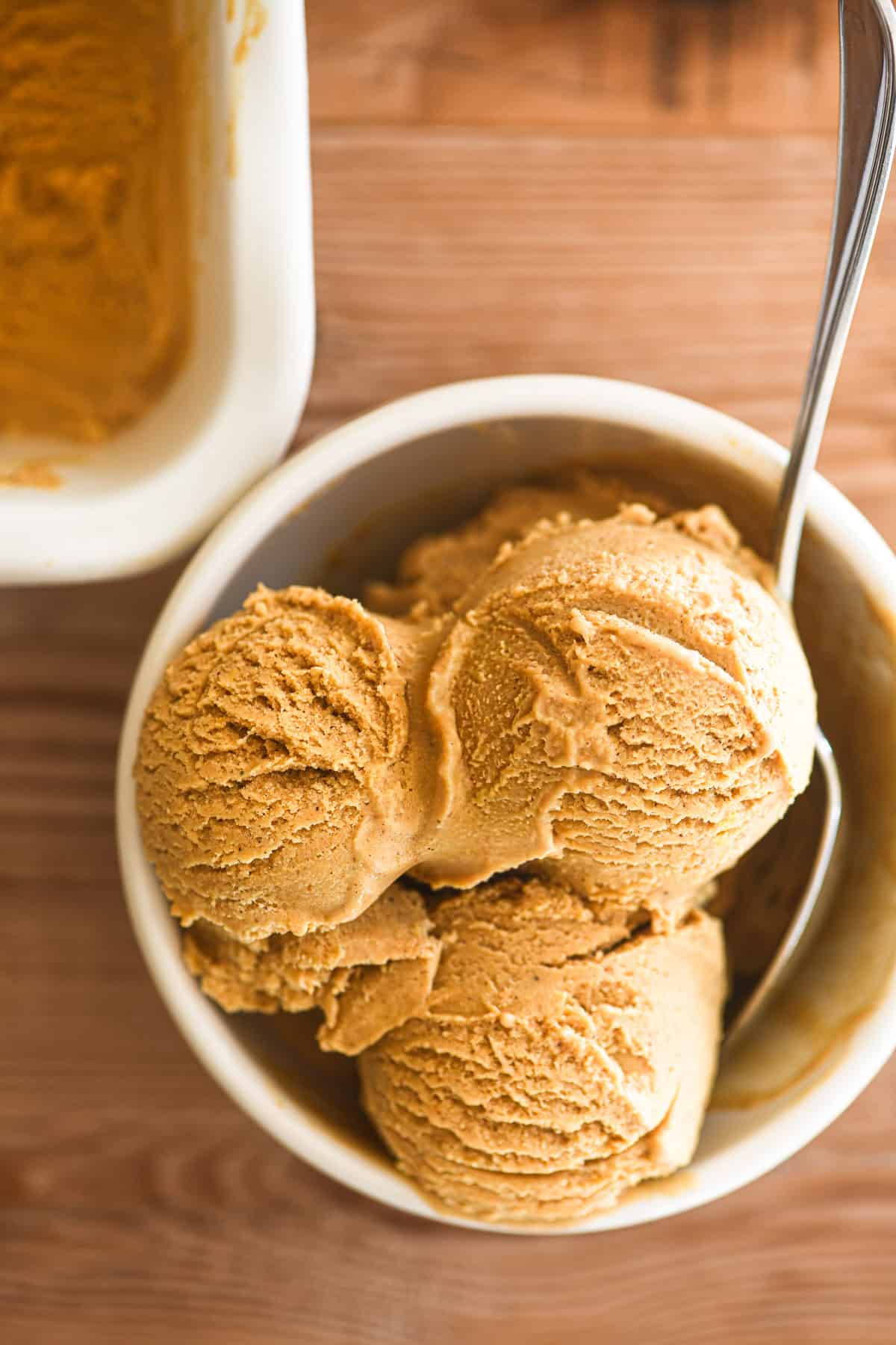 scoops of pumpkin ice cream in a small white dish.