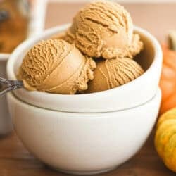pumpkin ice cream in a small bowl with pumpkins.