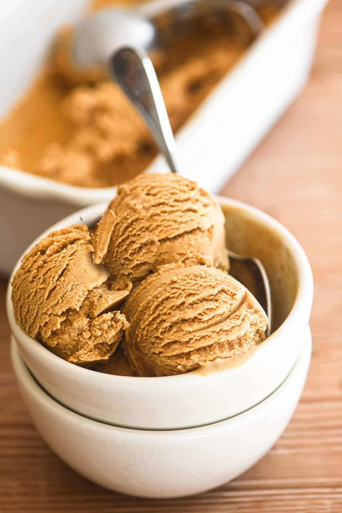 scoops of homemade pumpkin ice cream in a white bowl.