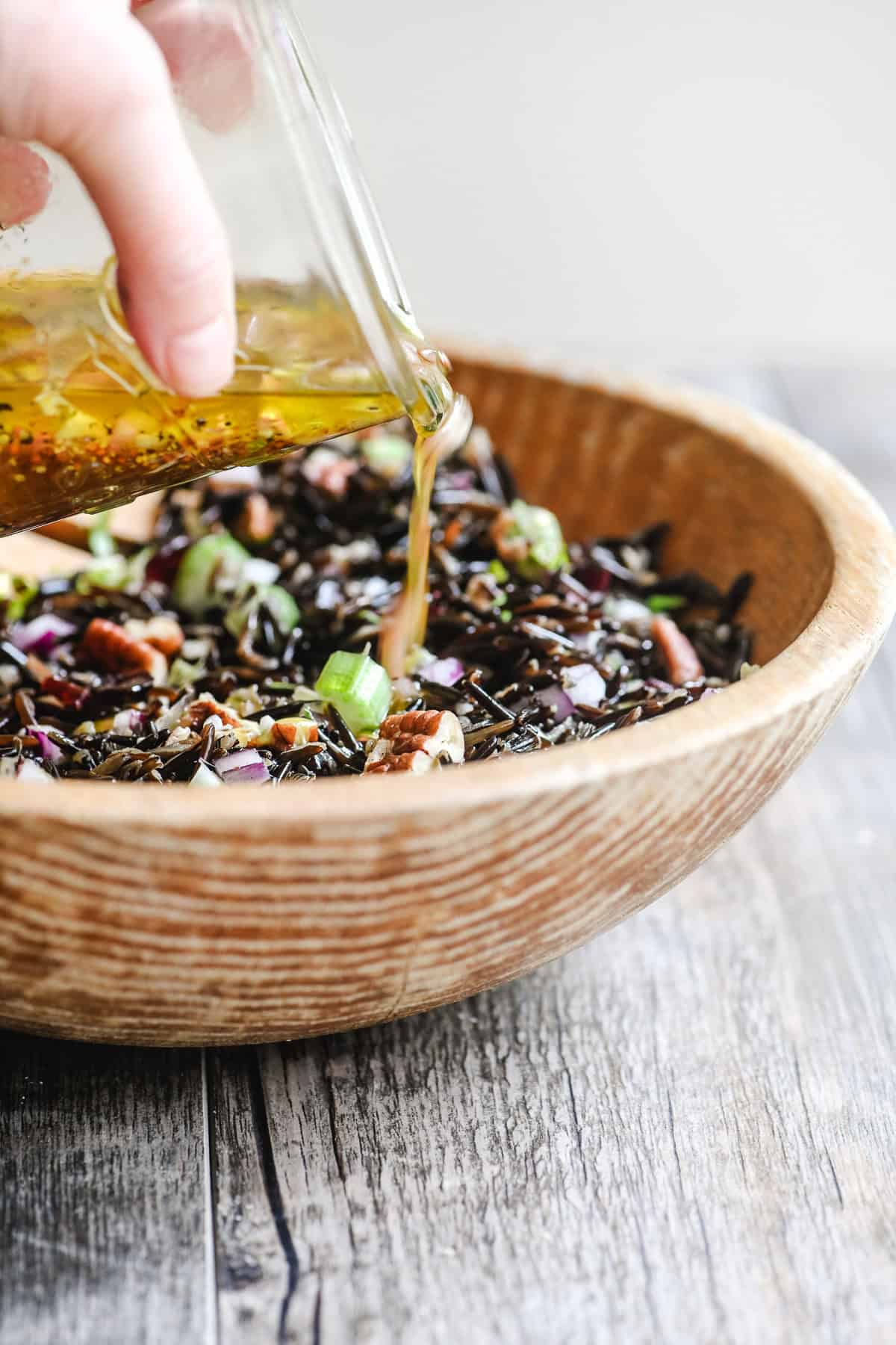 Adding dressing to a wild rice salad.