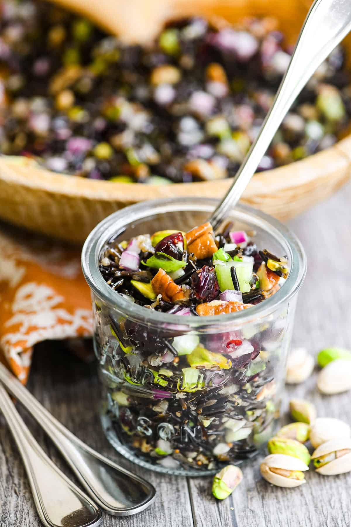 a jar of wild rice salad in front of the wooden bowl.