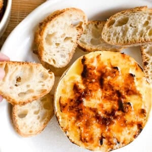 A wheel of Brûléed Brie with sliced baguette.