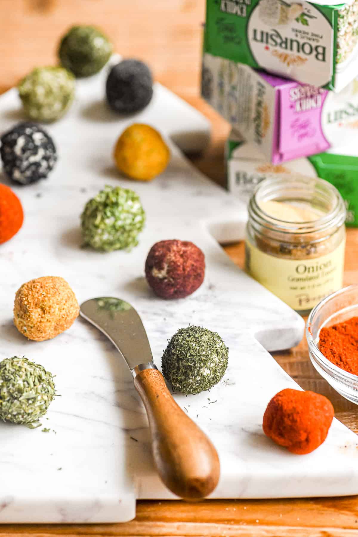 Making Boursin mini cheese balls on a marble tree shaped Holiday appetizer platter.