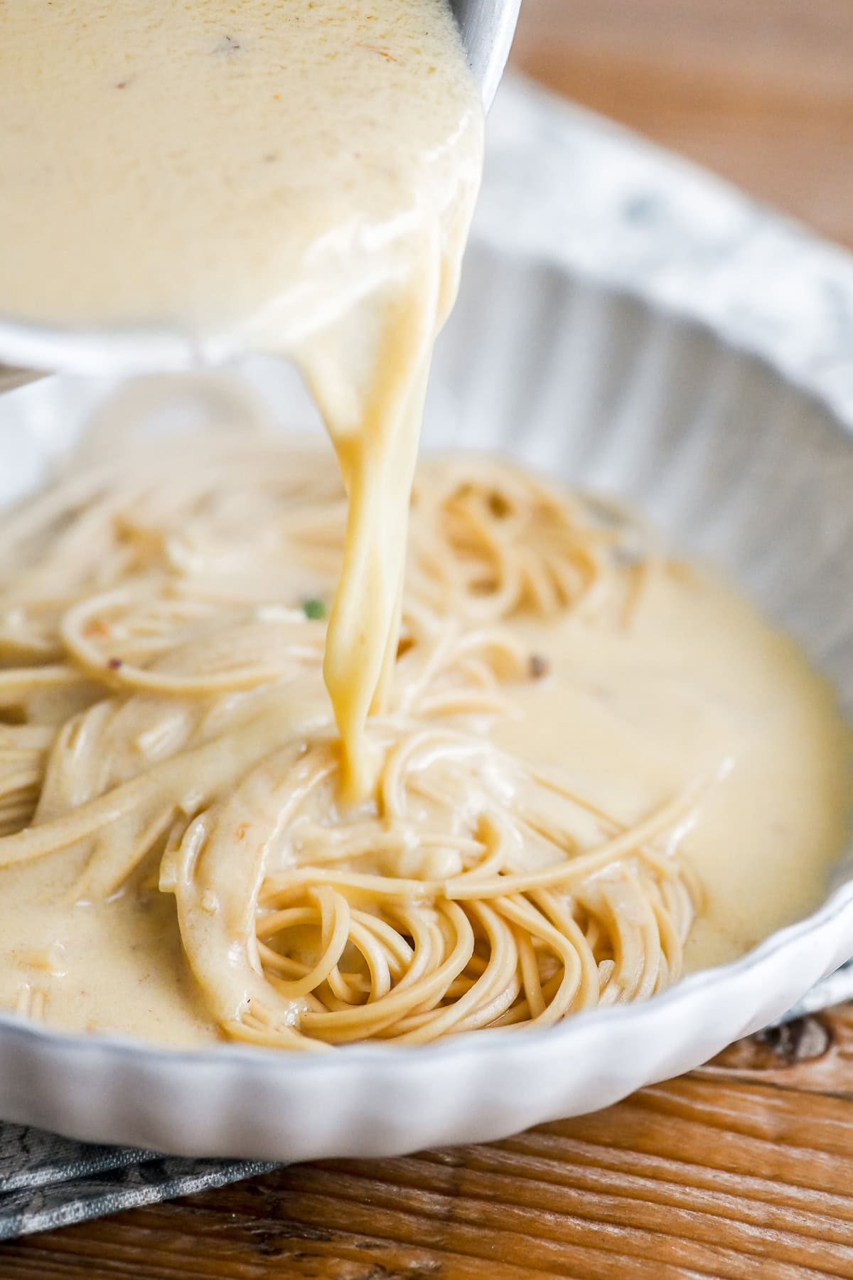 Pouring creamy ramen sauce over noodles.