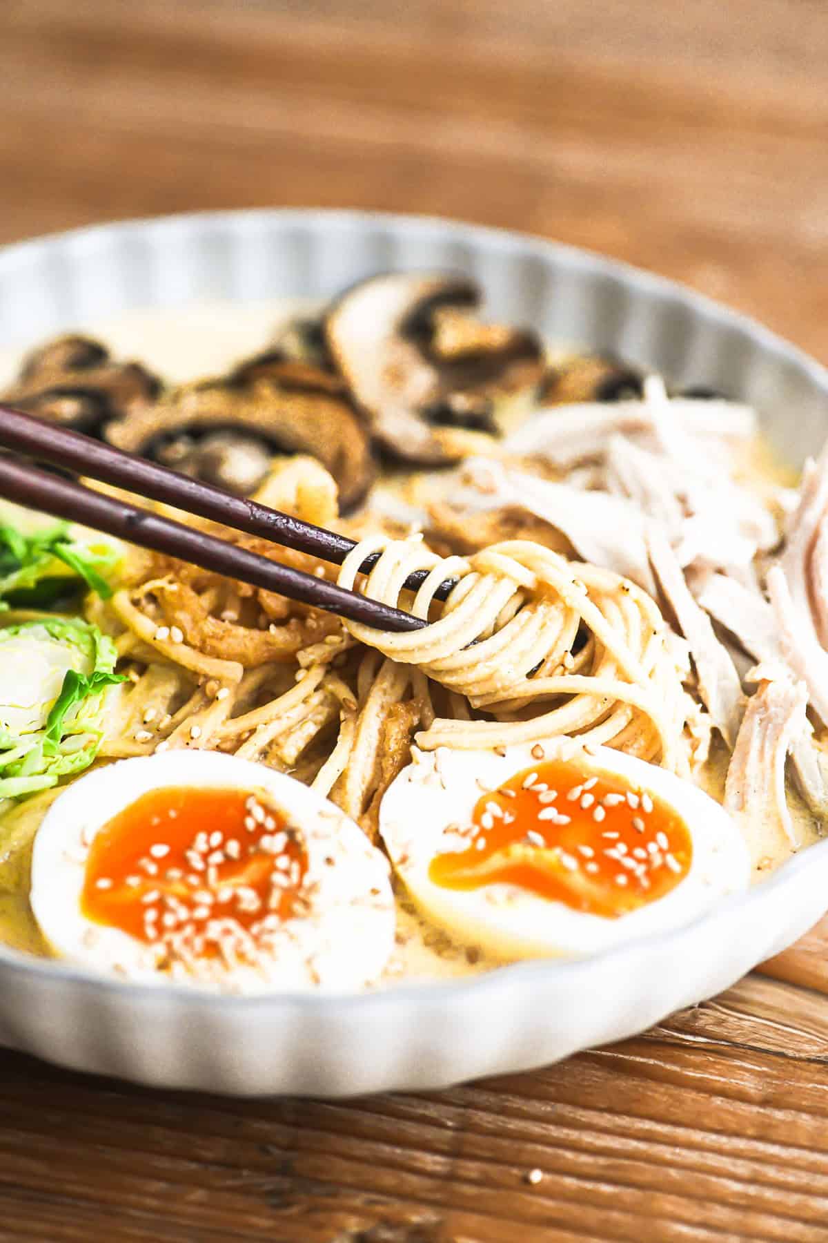creamy ramen with turkey and chili crisp in a bowl with shredded Brussels sprouts, mushrooms, and jammy eggs.
