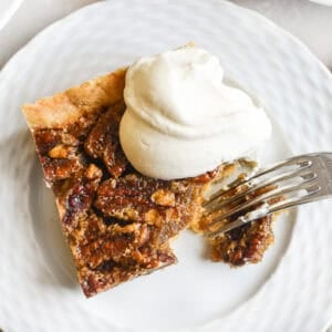Taking a bite of a pecan pie bar with whipped cream.