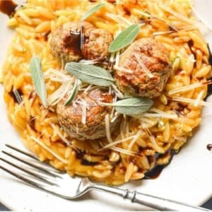 cheesy pumpkin orzo with turkey meatballs on a plate with fork.