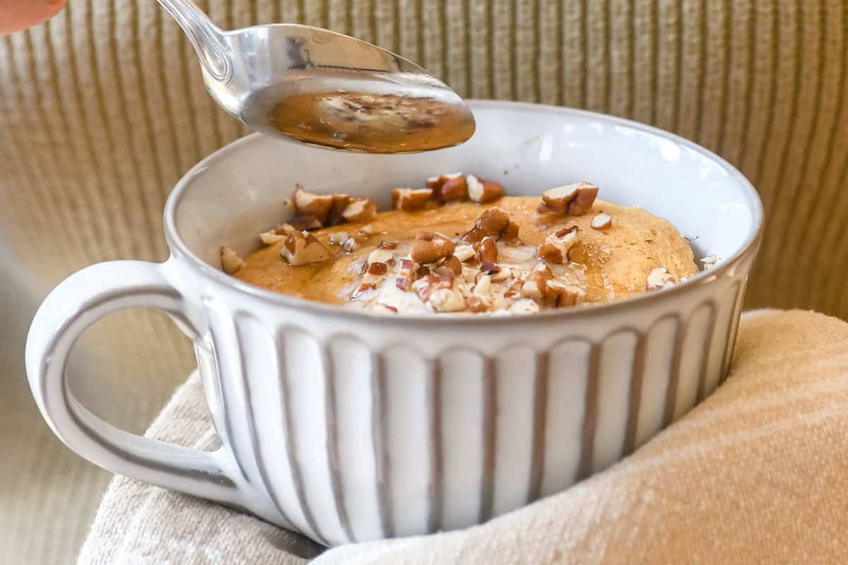 holding a pumpkin pancake bowl, with spoon poised to take a bite.