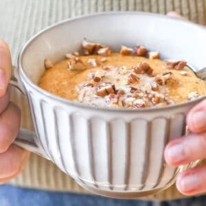 holding a pumpkin pancake bowl with butter, syrup and toasted pecans.