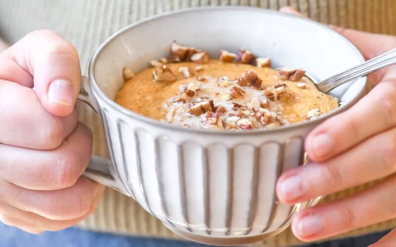 holding a pumpkin pancake bowl with butter, syrup and toasted pecans.