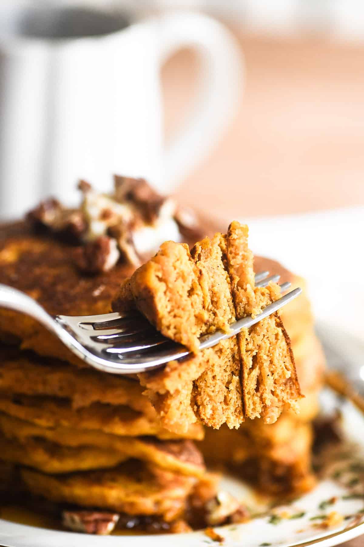 Taking a bite from a stack of pumpkin pancakes.