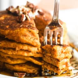 Taking a bite of a stack of pumpkin pancakes.