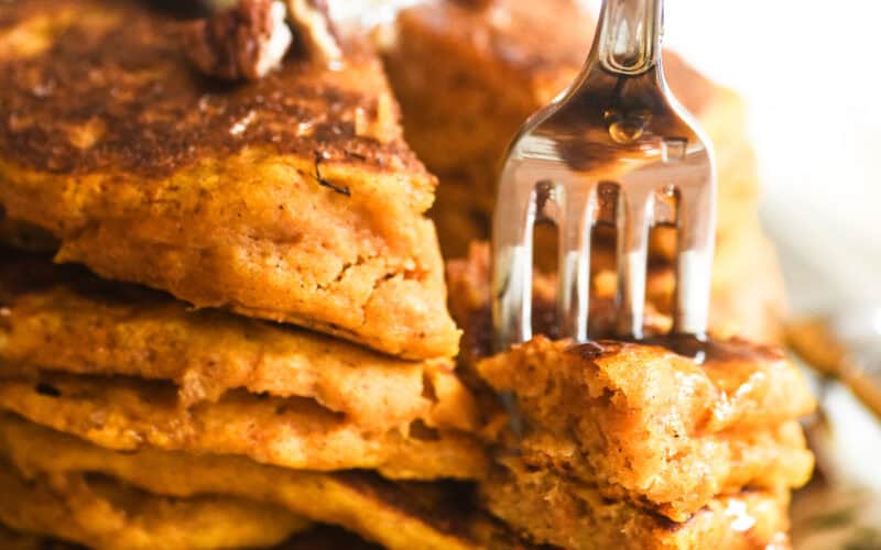 Taking a bite of a stack of pumpkin pancakes.