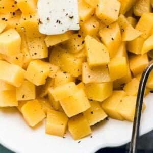 buttered rutabaga in a serving dish with spoon.