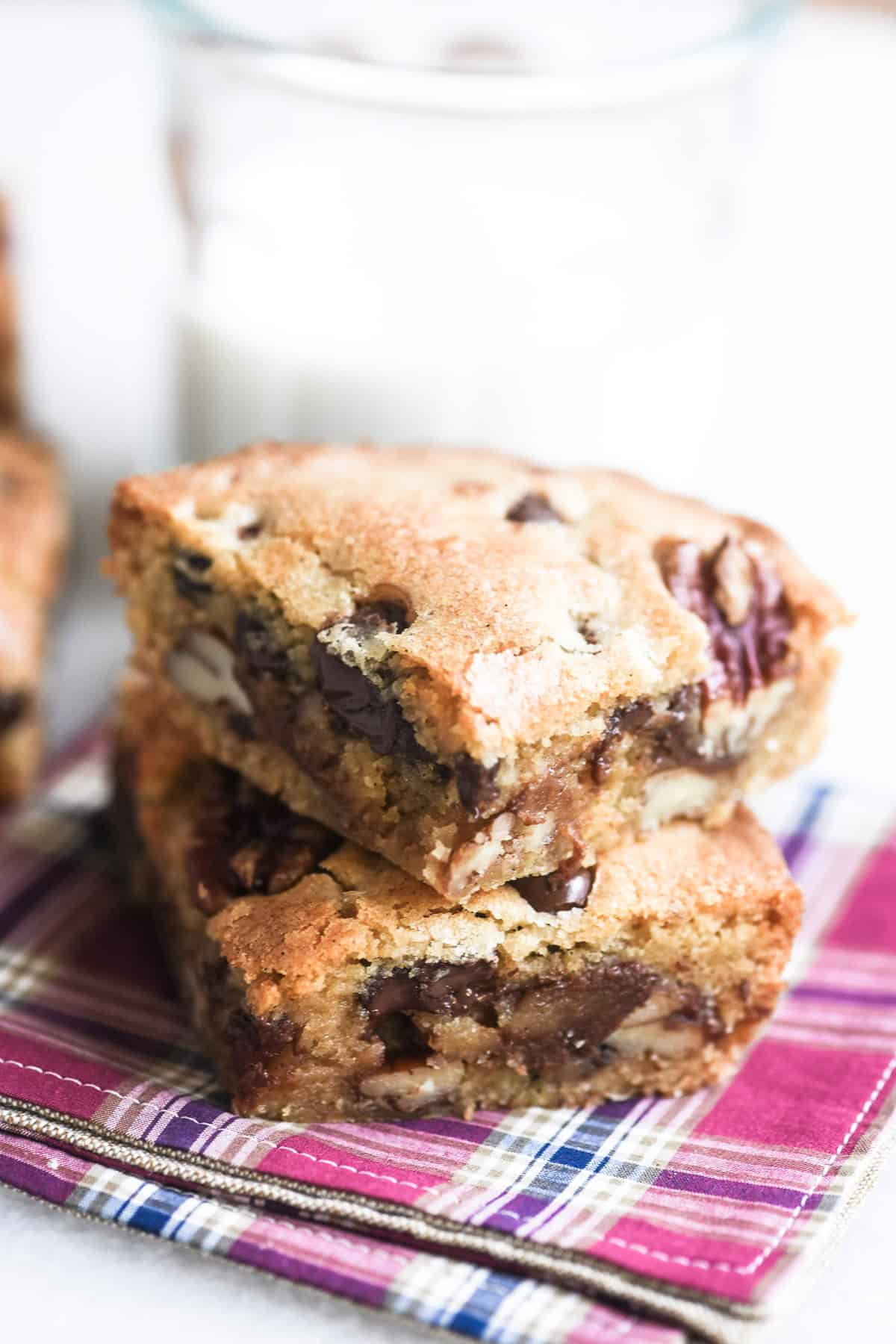 A stack of 2 bourbon butter pecan brownies, with glass of milk.