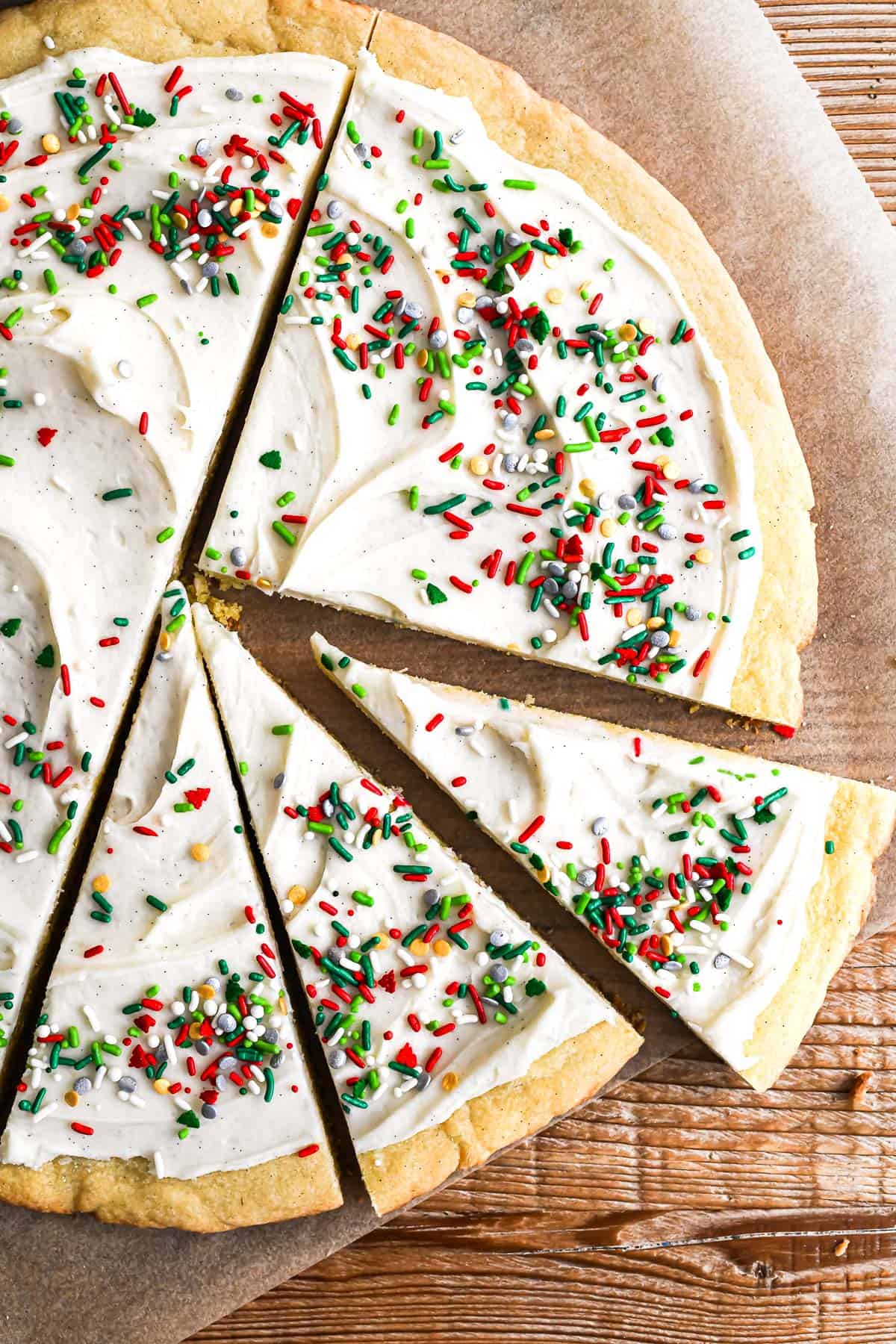 giant Christmas cookie pie being sliced into wedges on parchment paper.
