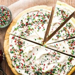 giant cookie pie in a pizza pan, frosted and covered with Christmas sprinkles.
