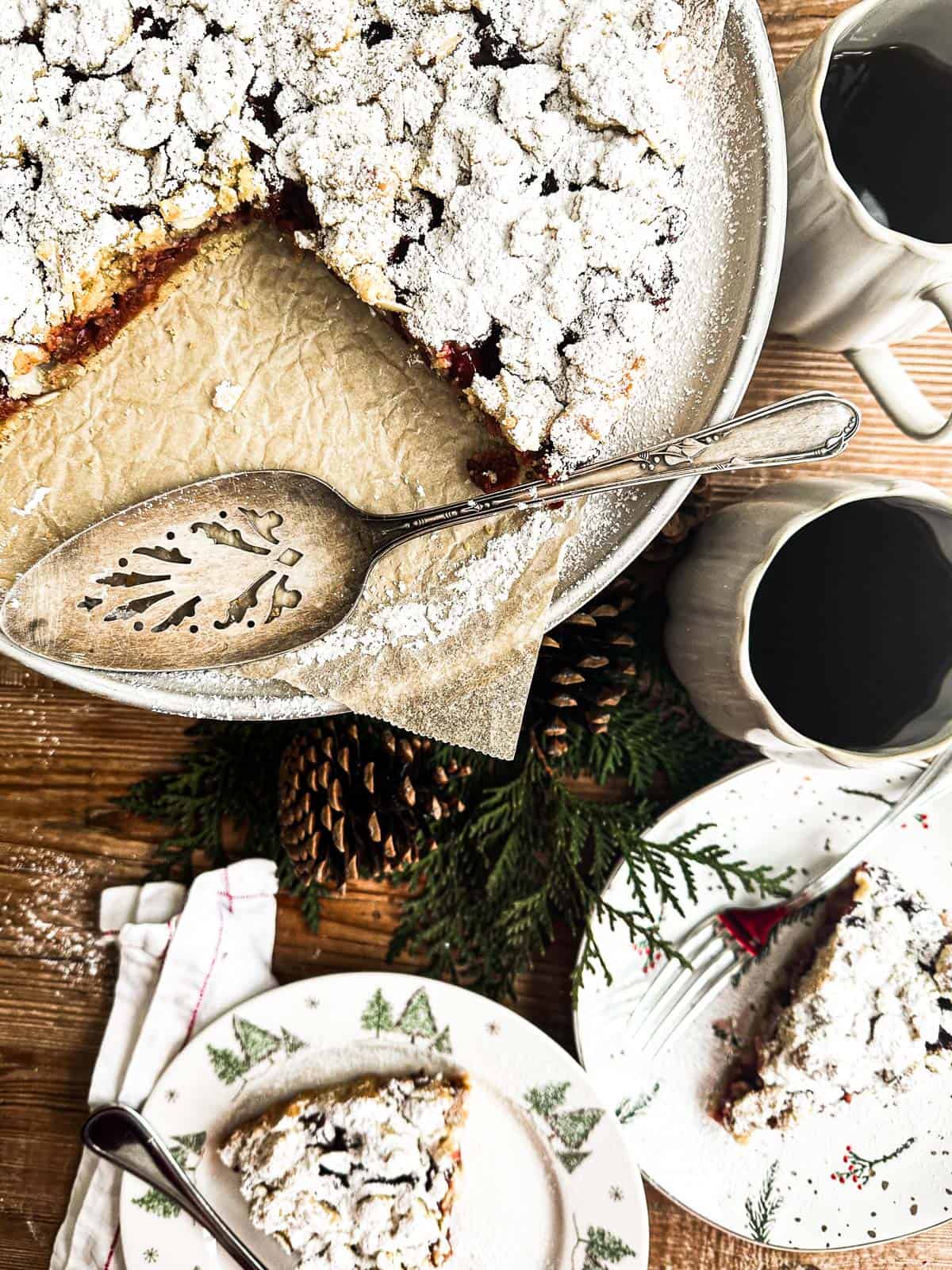 German sour cherry streusel cake on a cake stand with coffee cups.