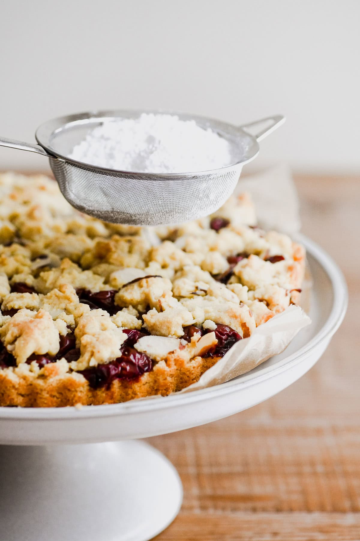 Dusting top of sour cherry streusel cake with powdered sugar.