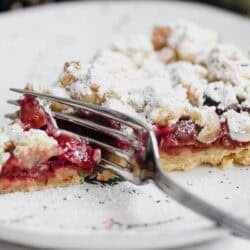 a slice of German sour cherry streusel cake on a plate with a fork.