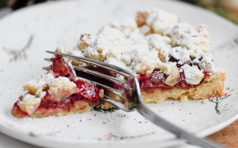 a slice of German sour cherry streusel cake on a plate with a fork.