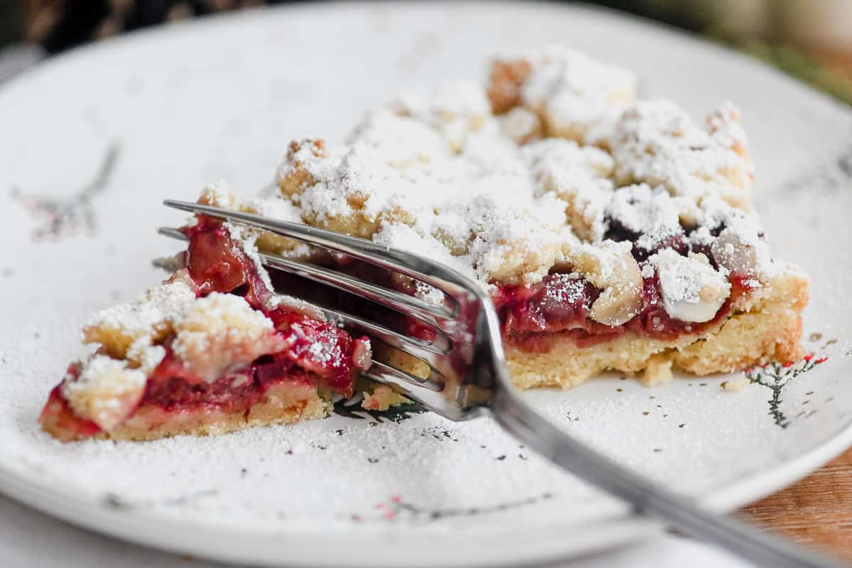 a slice of German sour cherry streusel cake on a plate with a fork.