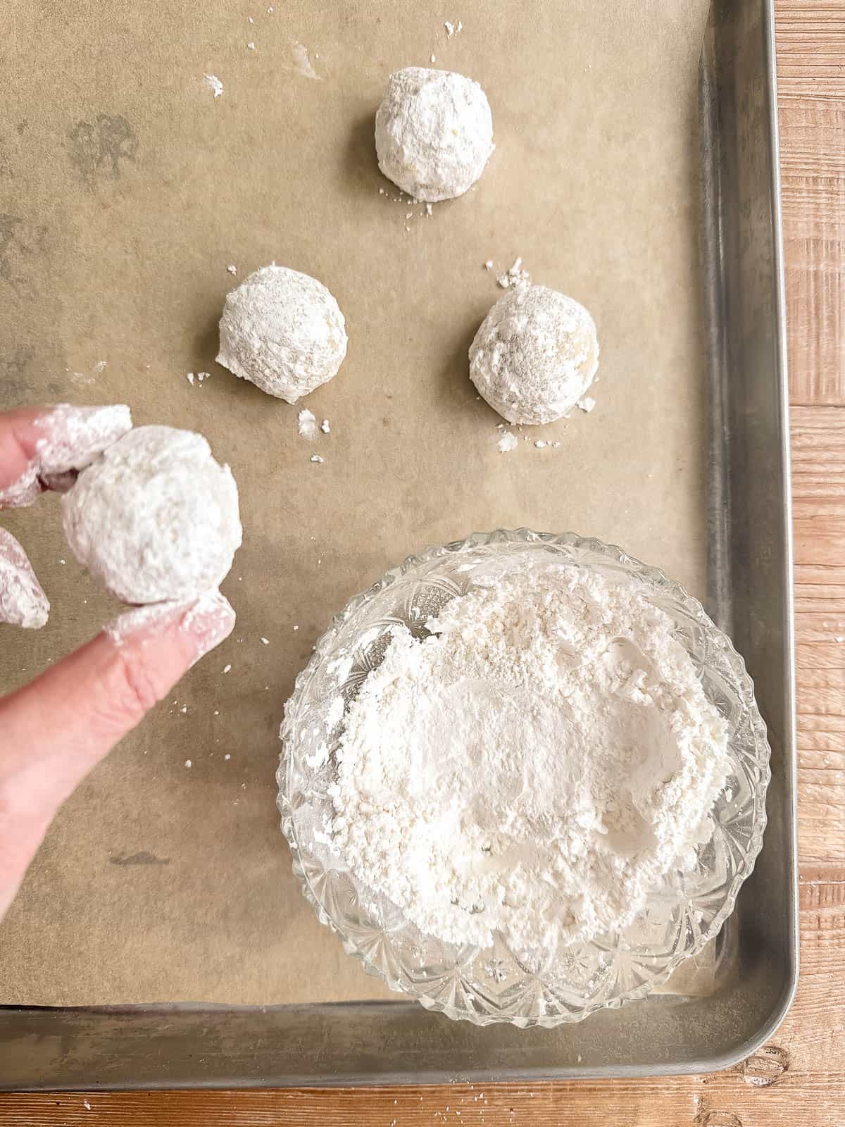 coating walnut ginger butterballs in powdered sugar