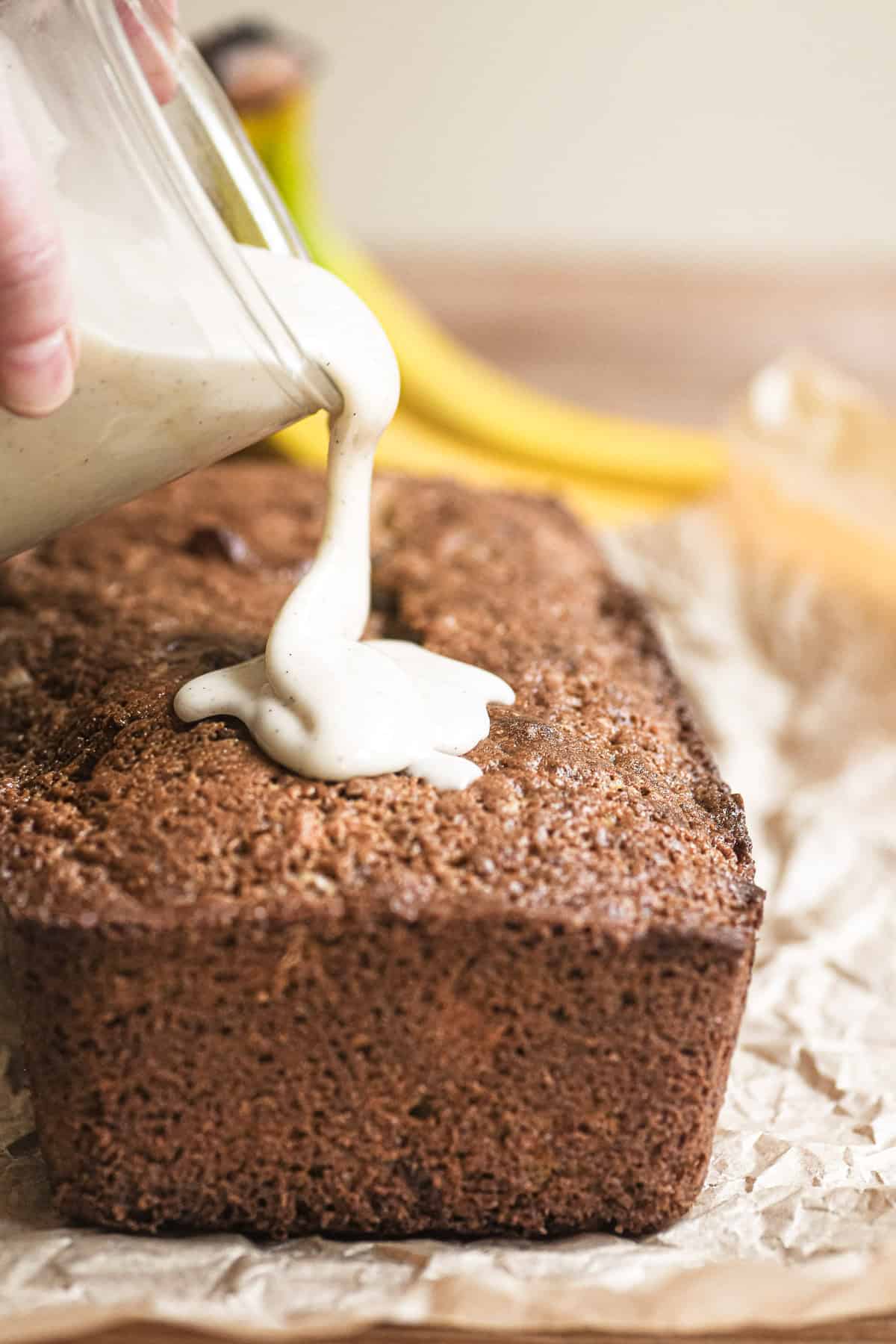 pouring glaze onto bourbon banana bread.