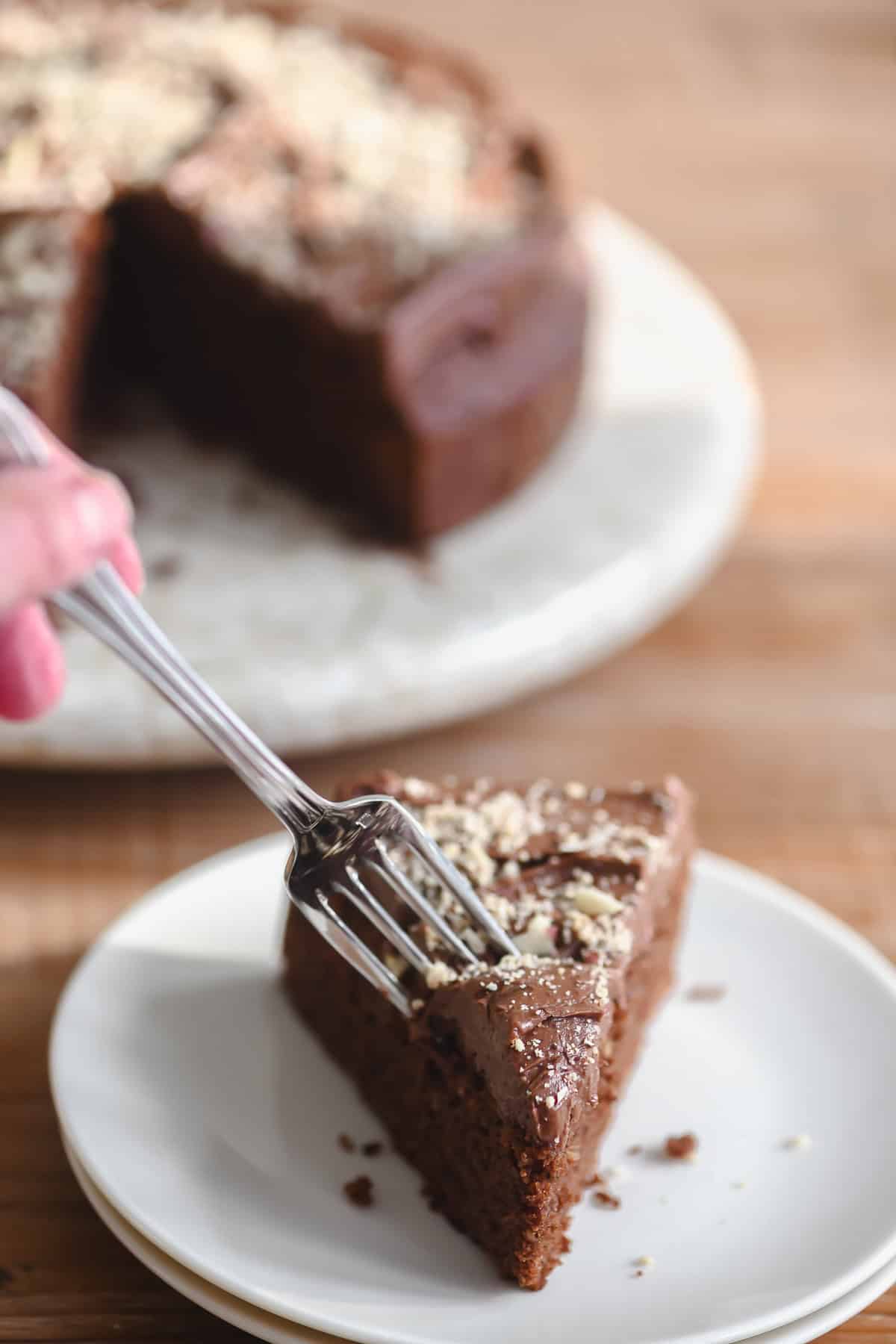 Putting a fork into a slice of dark chocolate hazelnut cake.