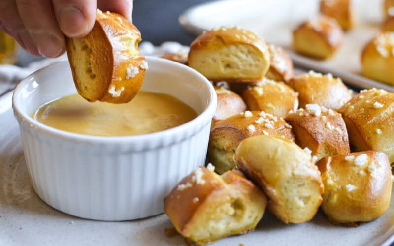 dipping a homemade pretzel bite into hot honey mustard sauce.