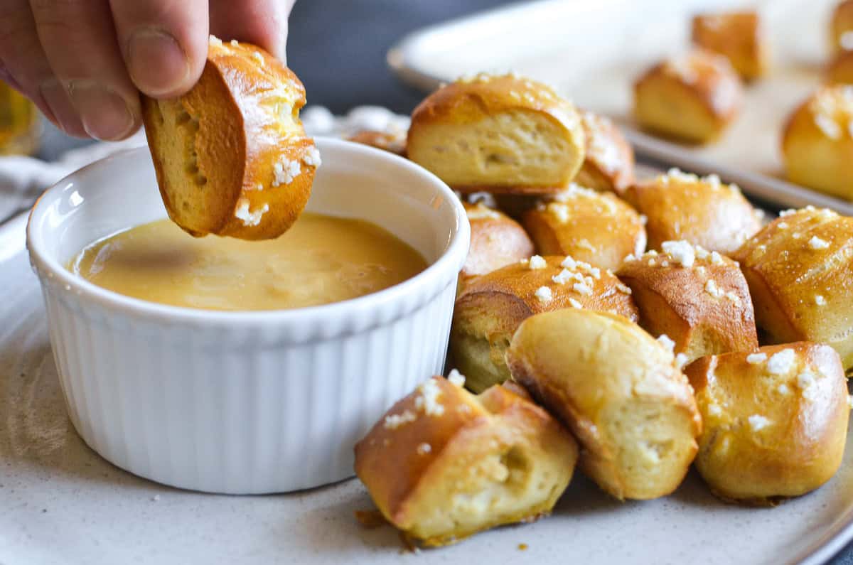 dipping a homemade pretzel bite into hot honey mustard sauce.