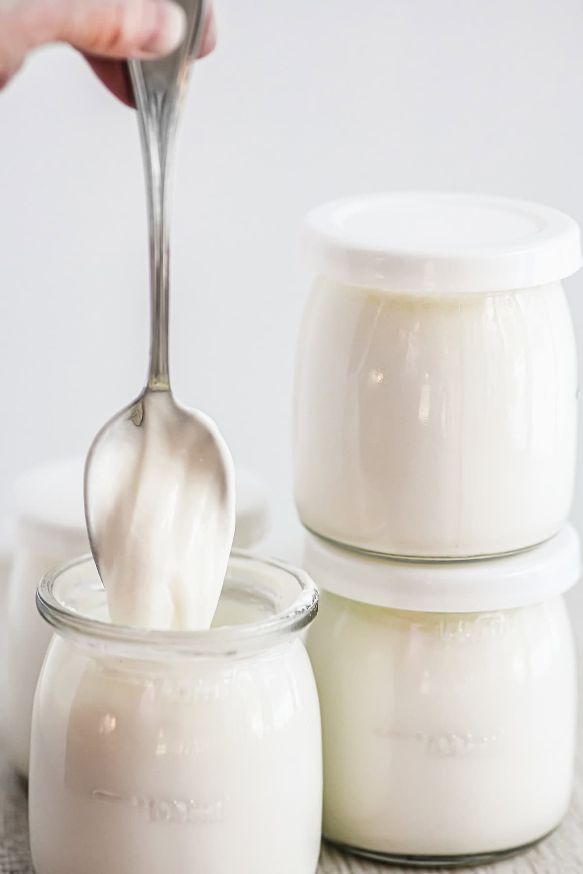 Spooning thick creamy homemade yogurt out of a small jar.