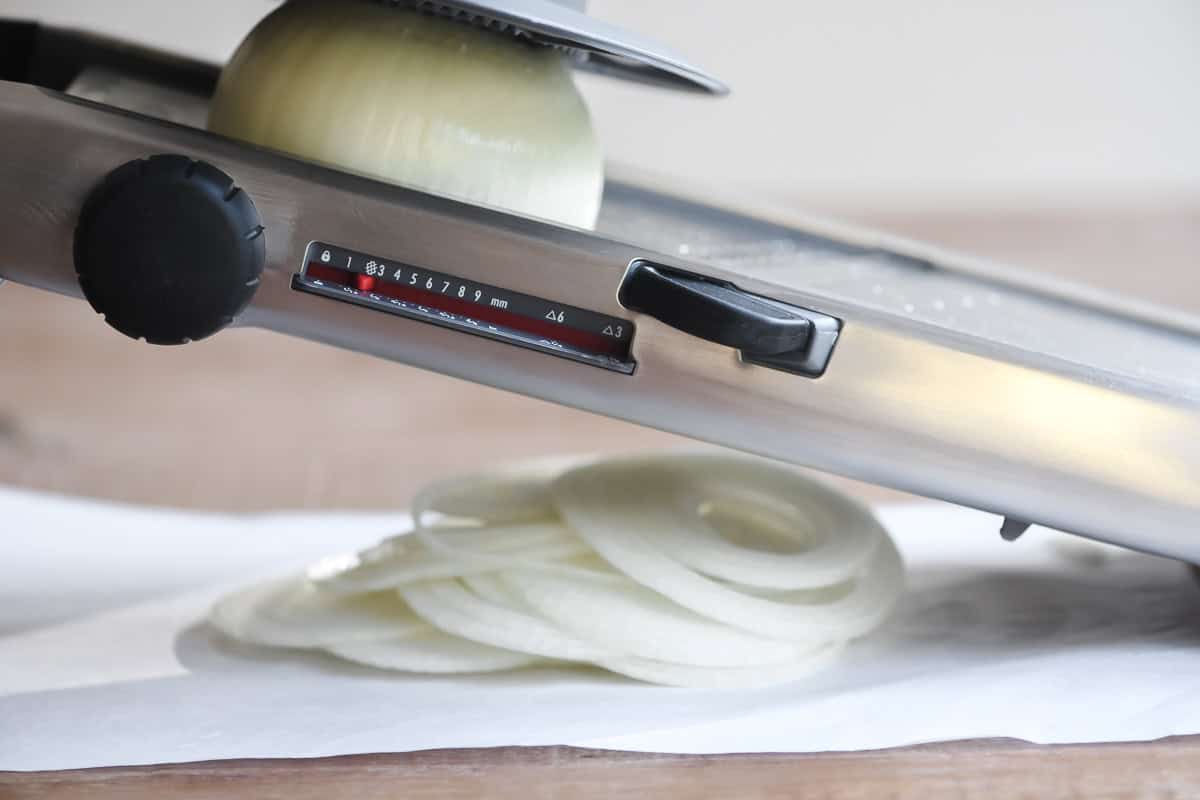 slicing onion on a mandoline for onions strings.