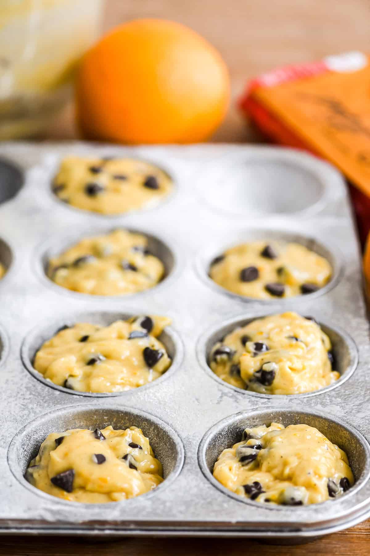 orange chocolate chip muffins batter in pan ready to bake.