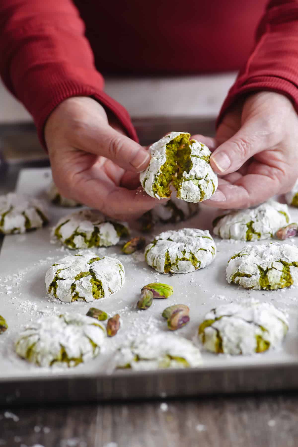 Breaking apart a pistachio amaretti cookie to show soft interior.