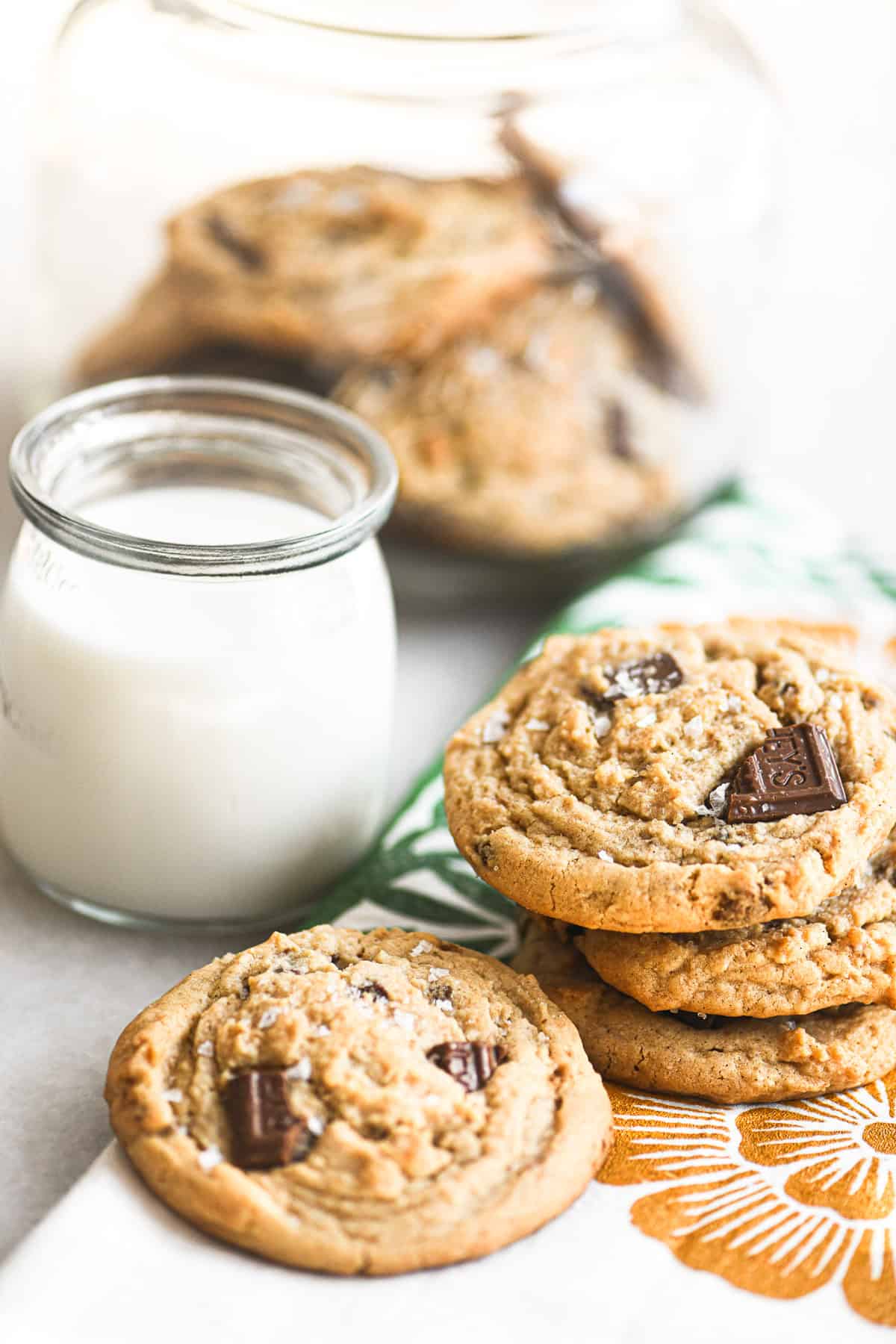 soft and chewy peanut butter chocolate chip cookies stacked with a glass of milk.