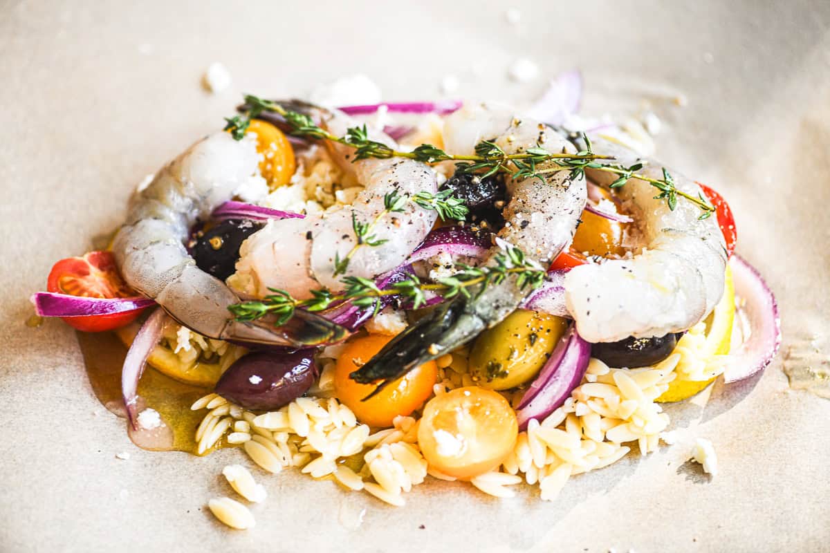 Greek shrimp packet being layered on parchment paper.