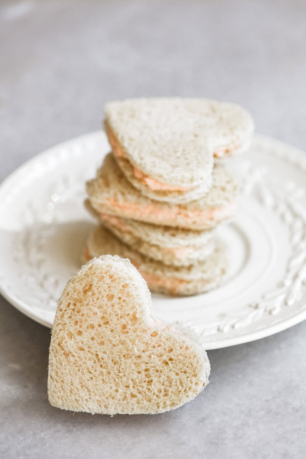 heart shaped smoked salmon tea sandwiches on a plate.