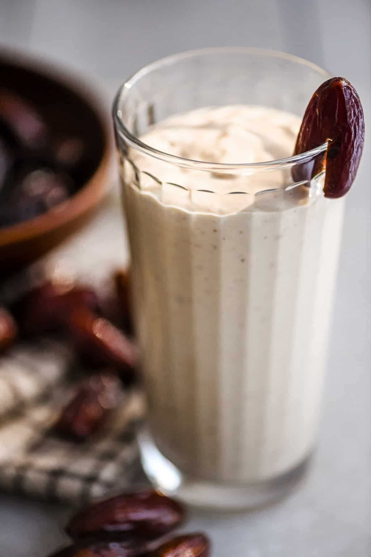 date shake smoothie in a tall glass with date garnish.